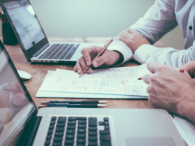 Due persone al lavoro su laptop e schemi cartacei durante l&rsquo;analisi dei requisiti